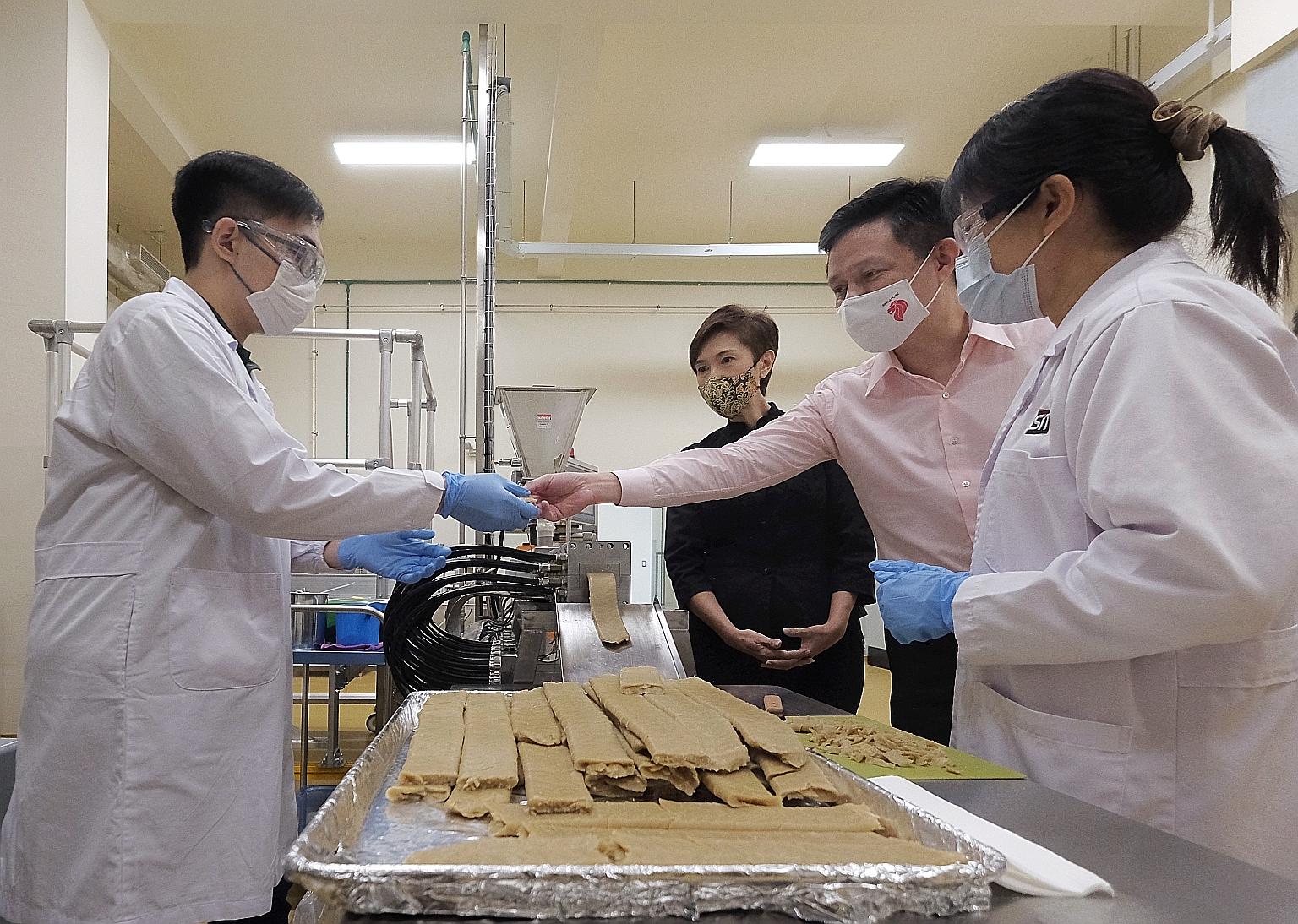 Minister for Trade and Industry Chan Chun Sing and Minister for Manpower Josephine Teo watching as an extruder machine made mock meat during a tour of food manufacturer KH Roberts' facility yesterday. The food manufacturing and service industry is ex
