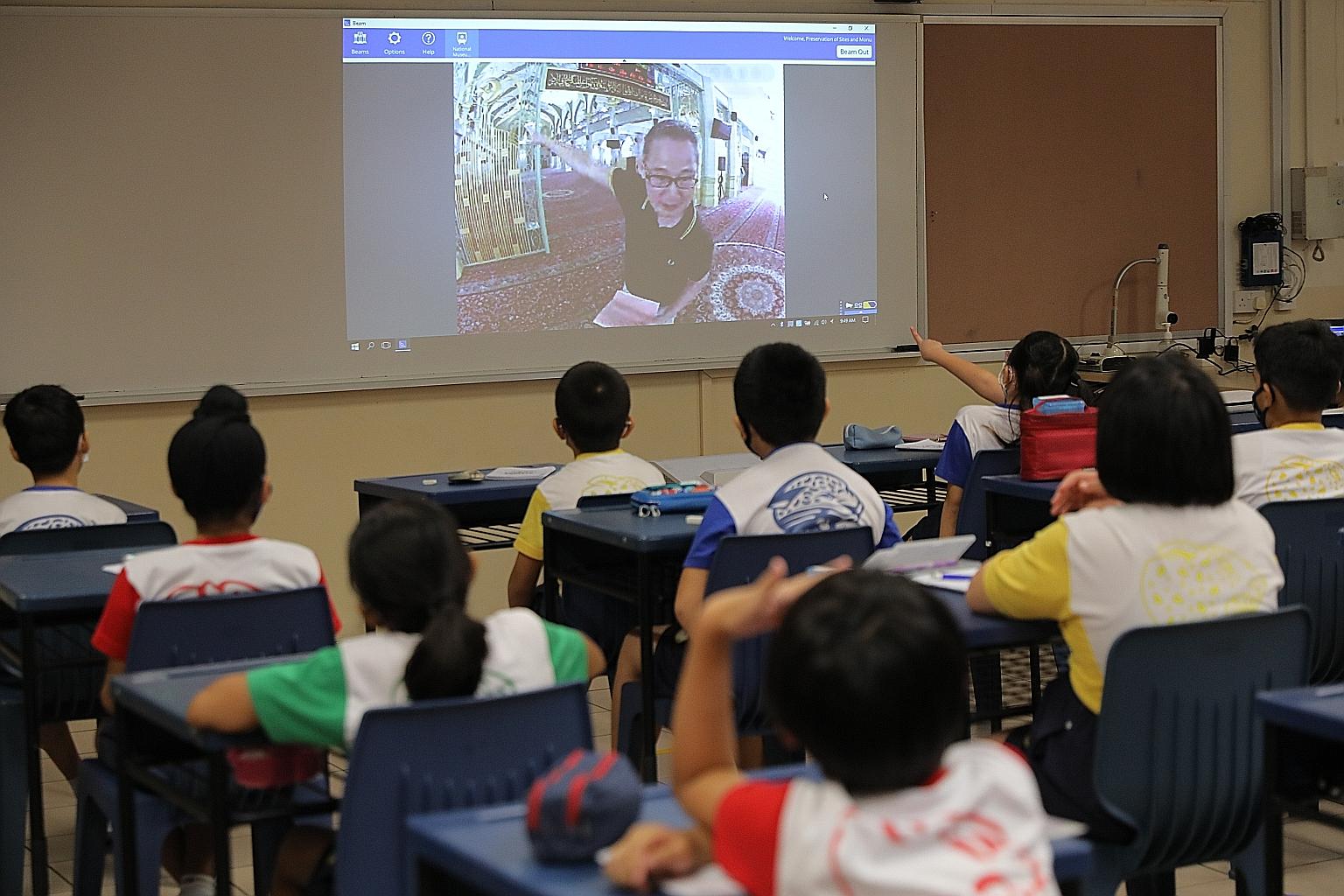 Pupils of Qihua Primary School taking a virtual tour of Sultan Mosque yesterday with the help of a remotely controlled mobile monitor and Mr Robert Chan (on screen), 70, a volunteer guide with the National Heritage Board's Preservation of Sites and M