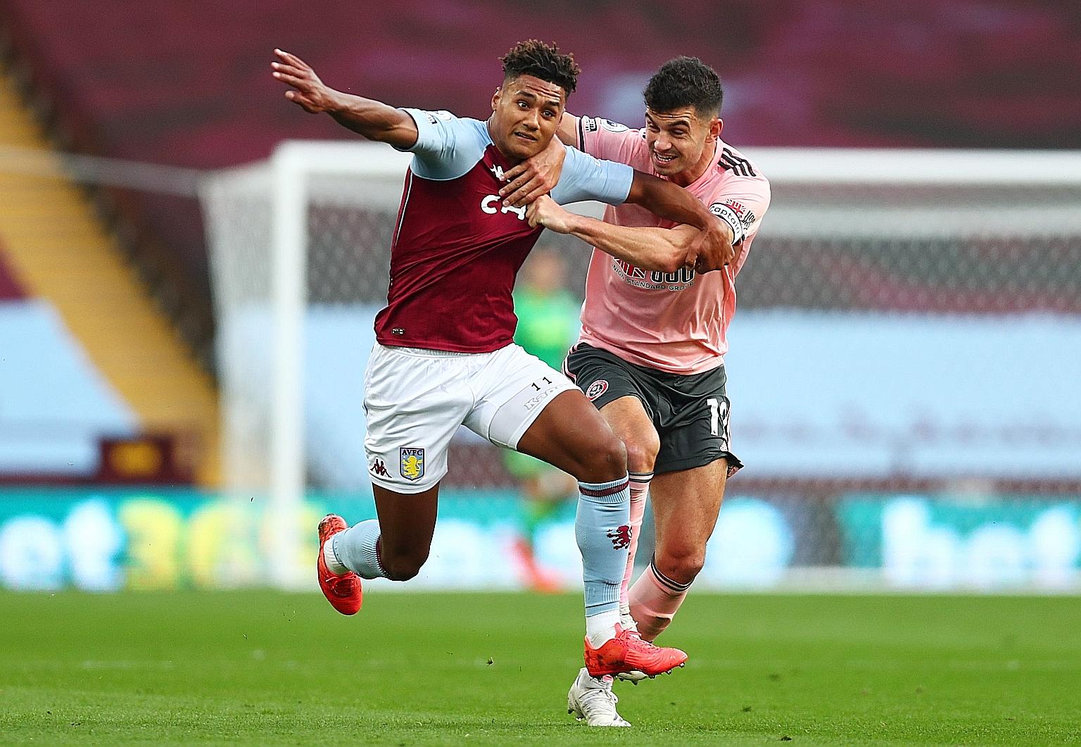 Sheffield United's John Egan (right) tugging on the shirt of Aston Villa striker Ollie Watkins. The defender was sent off for his troubles, leaving the 10-man Blades to lose their second Premier League game of the season 1-0. PHOTO: REUTERS