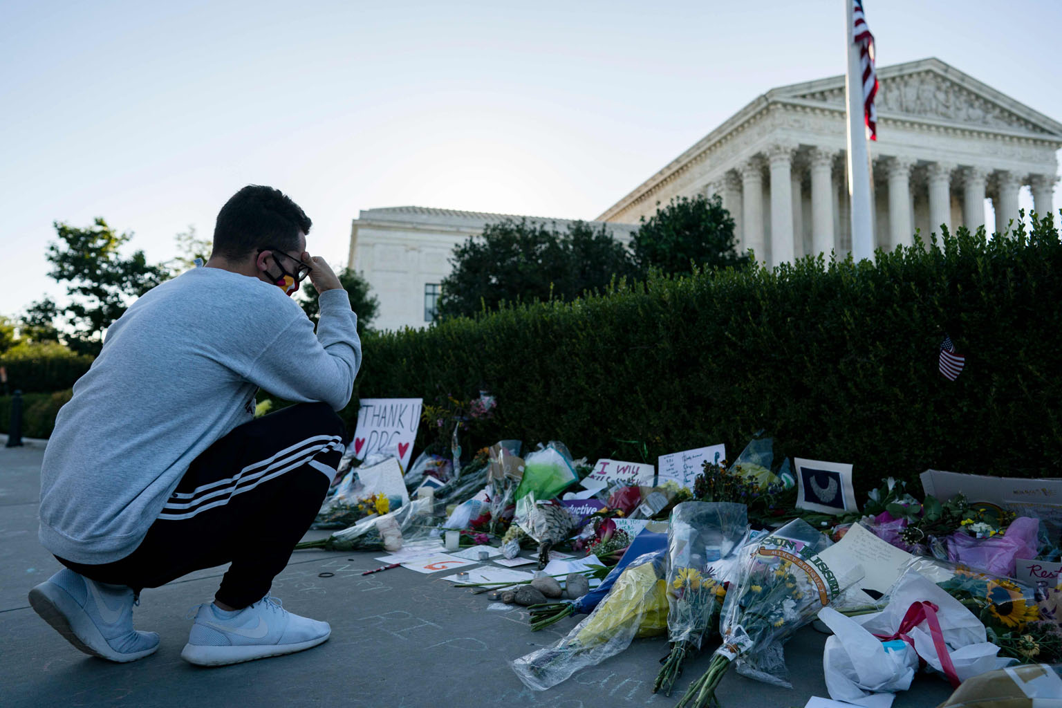 A mourner at a makeshift memorial for the late US Supreme Court Justice Ruth Bader Ginsburg near the steps of the courthouse in Washington on Monday. Flowers, handwritten notes, candles and messages written in chalk wrapped around the side of the bui