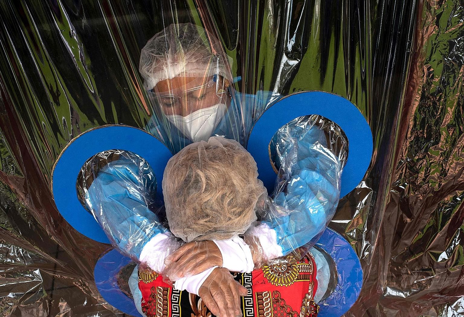 Ms Maria Hernandez, 38, embracing her aunt through a plastic curtain at a nursing home in San Salvador, El Salvador, earlier this month. Dr Michael Ryan from the WHO has suggested the disparate performances of different countries in handling the pand