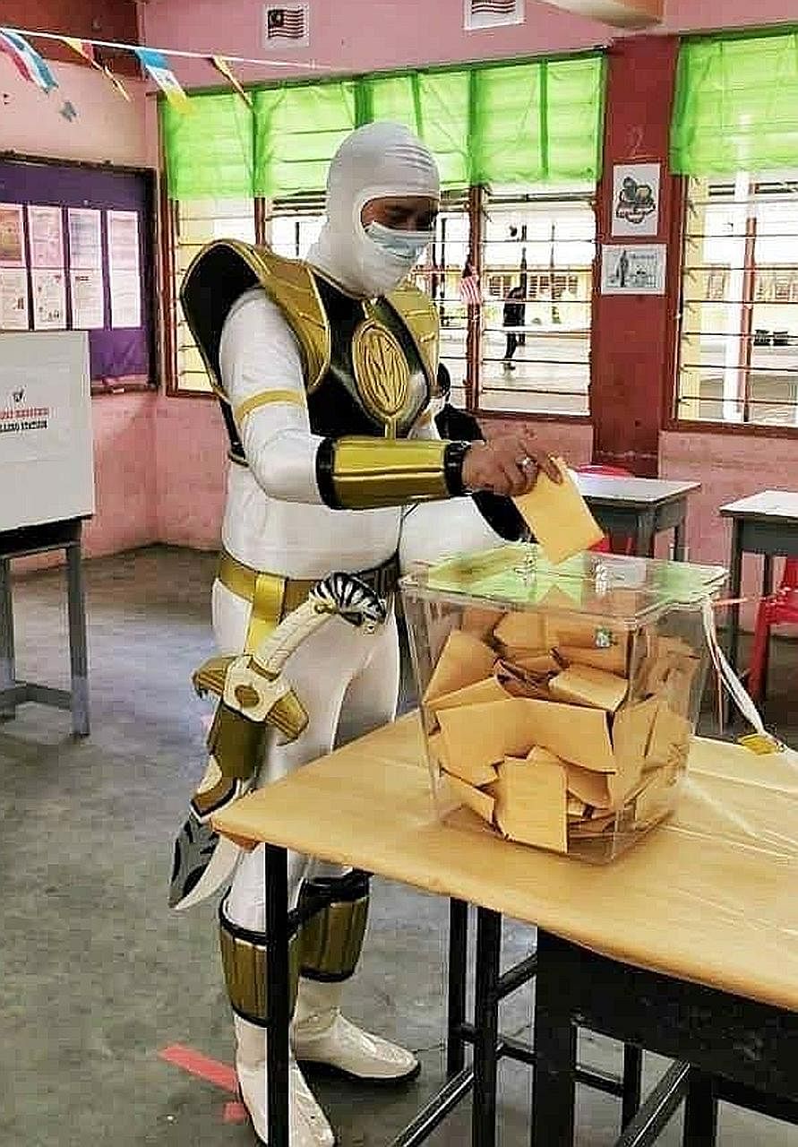 A Malaysian in a Power Ranger costume (above) casting his vote yesterday at the polling centre in SMK Tansau, Penampang, while voters at SRK Sacred Heart (right) in Kota Kinabalu waited to vote. The Sabah election was called after an ally of Prime Mi