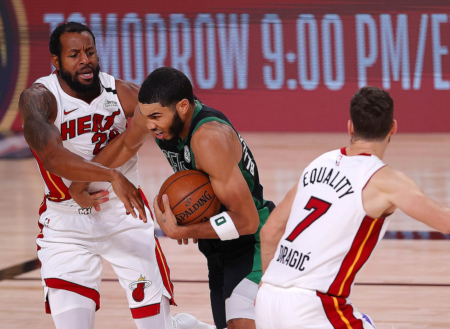 Boston Celtics' Jayson Tatum driving past two Miami Heat players during Game 5 of the Eastern Conference Finals. PHOTO: AGENCE FRANCE-PRESSE