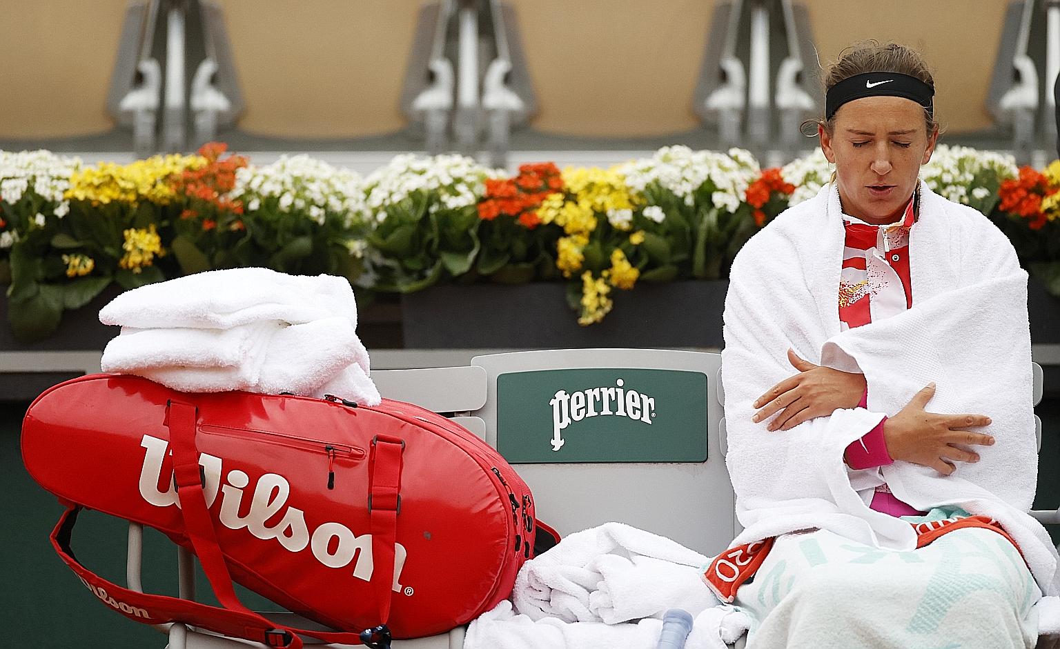 World No. 14 Victoria Azarenka huddling under her towel for warmth during her first-round win. It was 10 deg C at Roland Garros yesterday. PHOTO: REUTERS