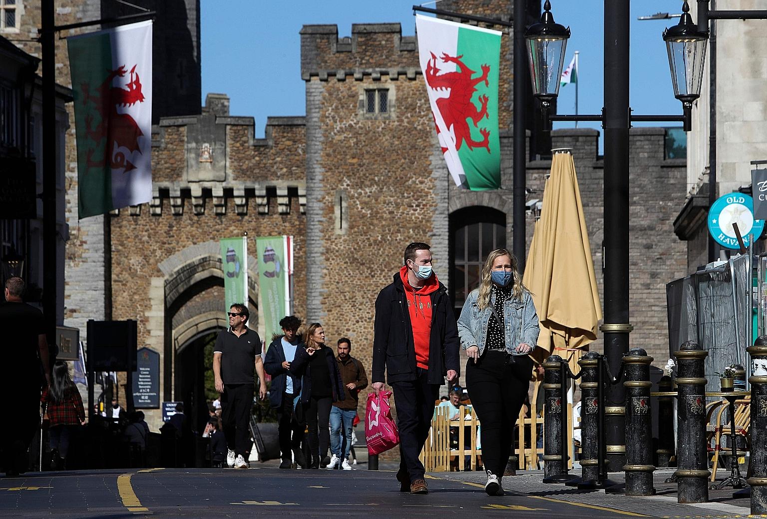 People walking in the city of Cardiff, in the south of Wales, on Sunday. A British newspaper reported that ministers were preparing to enforce a total social lockdown across much of northern England and potentially London.