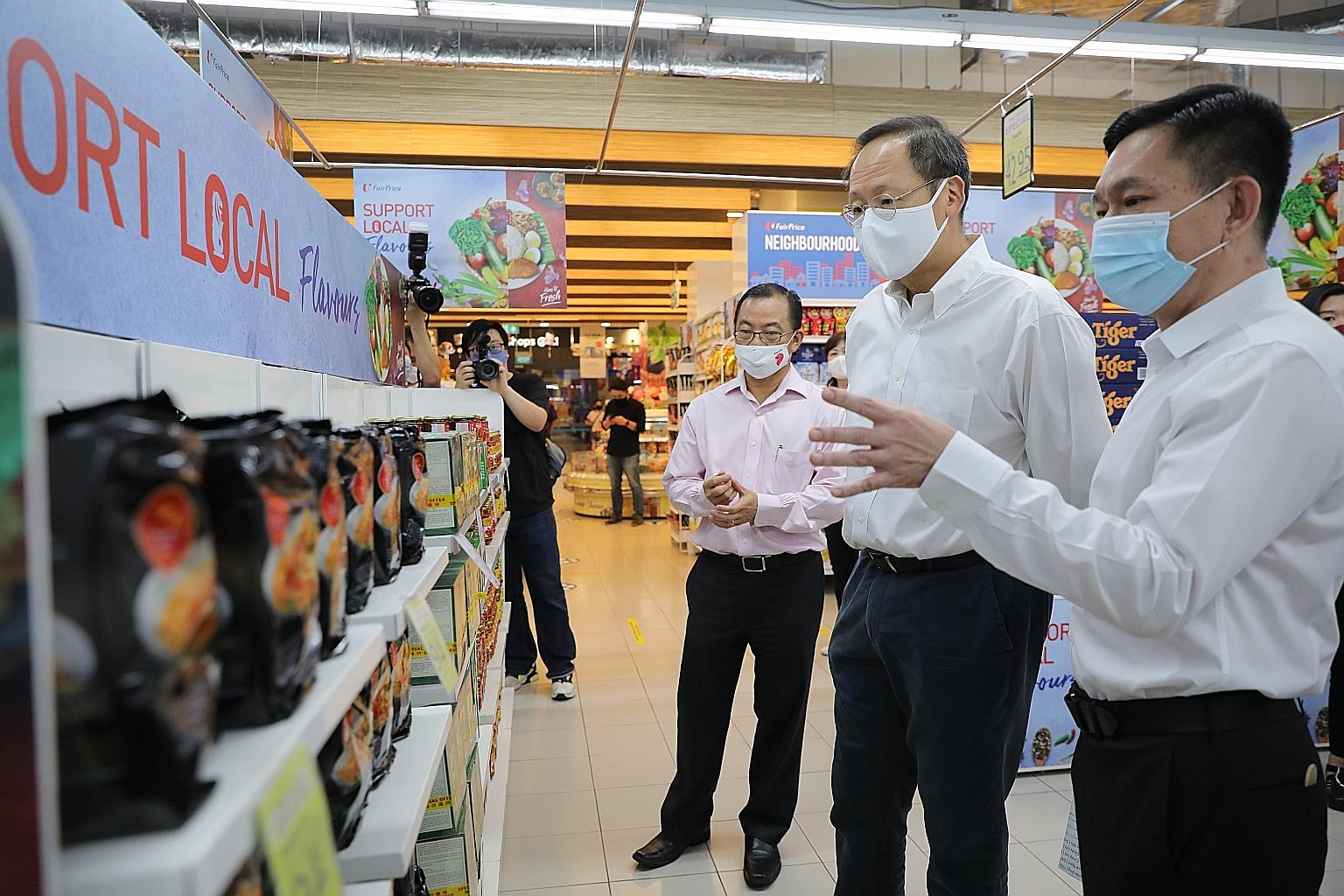 Second Minister for Trade and Industry and Manpower Tan See Leng (second from right) and FairPrice group chief executive Seah Kian Peng (third from right) checking out the locally produced food items on sale at FairPrice's Our Tampines Hub outlet on