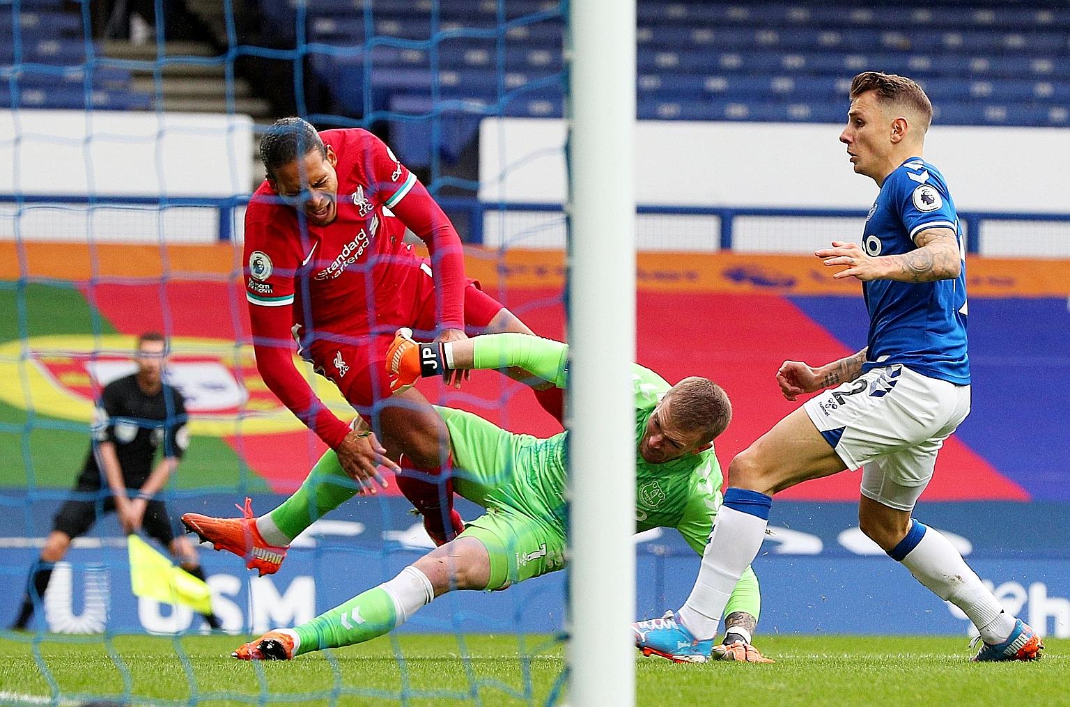 Liverpool defender Virgil van Dijk going down in pain after an overly aggressive challenge by Everton goalkeeper Jordan Pickford.