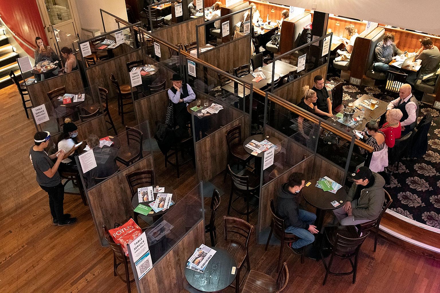A member of staff wearing a face shield while taking orders on Sunday at a London pub where tables are separated by Perspex screens as part of social distancing measures. British Prime Minister Boris Johnson is facing some calls to abandon his strate