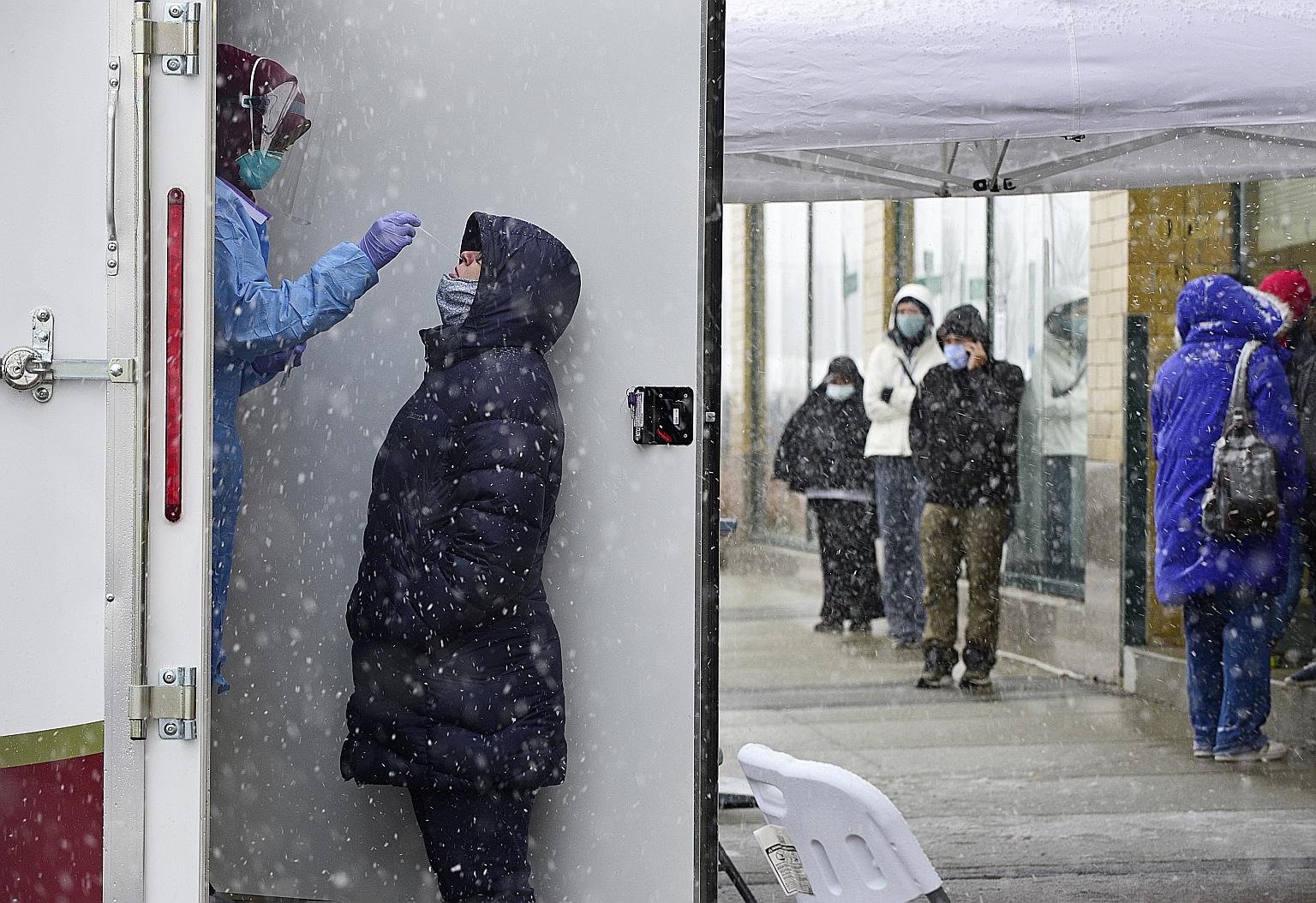A healthcare worker administering a Covid-19 test amid snowfall in Fargo, North Dakota, on Tuesday. The latest wave of infection in the US threatens to be the worst of the pandemic yet, coming as cooler weather forces people indoors and with many Ame