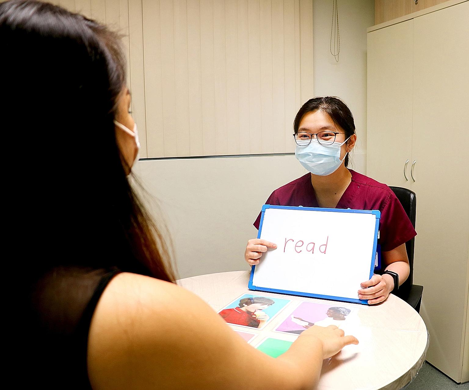 Ms Weng Wanxin (left), a senior speech therapist at Alexandra Hospital, conducting a therapy session for a patient with aphasia. The task involves matching a written word to a picture, which trains reading comprehension.