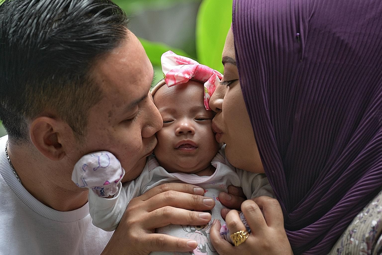Seven-month-old Nur Zaiya - seen here with her parents Rohani Mustani, 37, and Muhammad Saufi Yusoff, 36 - was born on March 27 and is the smallest baby to be discharged from the National University Hospital. The couple have two other daughters, aged