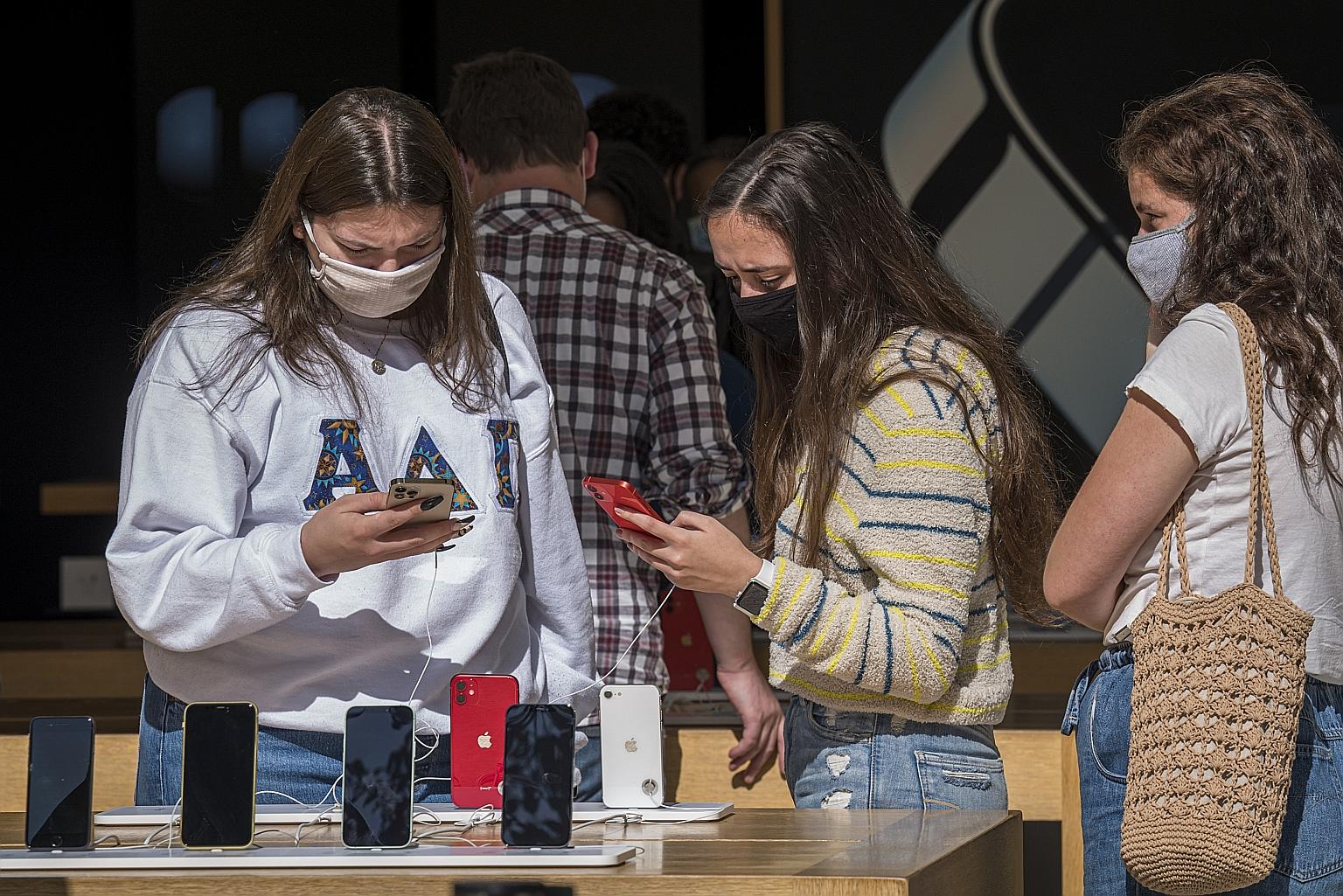 People checking out the new iPhones at an Apple store in San Francisco earlier this month. Apple has reported quarterly results that topped Wall Street estimates after record sales of Macs and services made up for a delayed iPhone 12 launch. But its