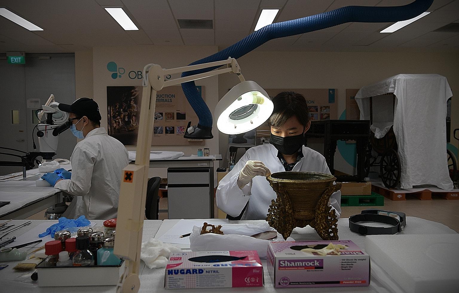 Conservator Claire Lim of the Heritage Conservation Centre getting a mid-20th century rice basket ready for exhibition. The HCC, which is overseen by the National Heritage Board, stores, preserves and distributes the more than 200,000 artefacts and p