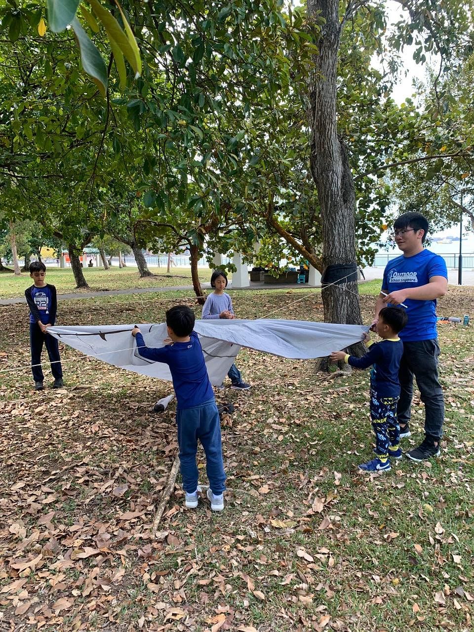 Children learning to set up a tent before Covid-19 as part of Outdoor School Singapore's Tall Timber programme. Mr Glen Poh, who teaches wilderness survival courses, building a shelter with sticks. Ms Gina Pang, Mr Raymond Seow and their sons Ethan (