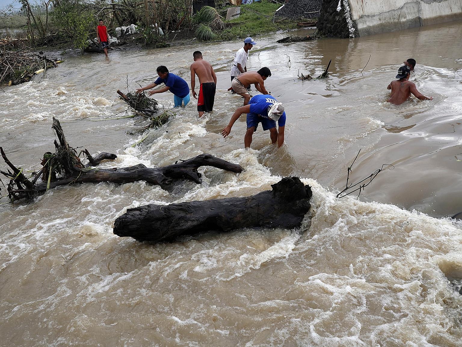 Debris being cleared after flood waters hit a town in Camarines Sur province yesterday.