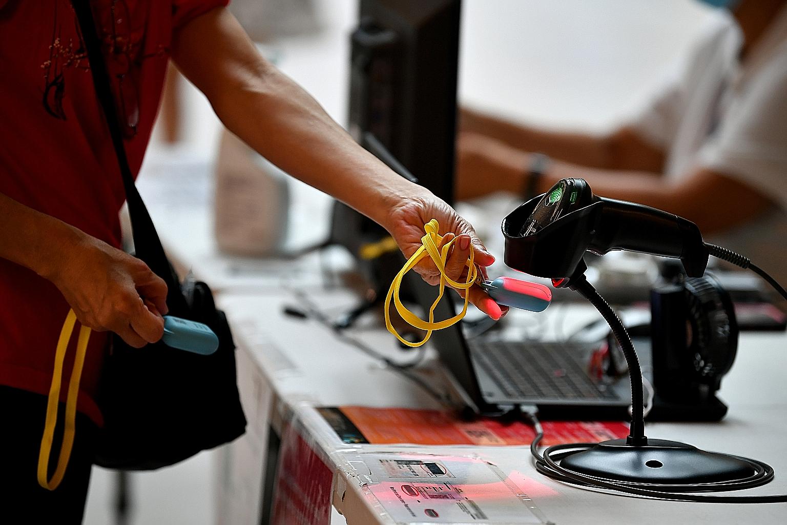 A shopper using a TraceTogether token to check in at SingPost Centre on Tuesday. Compulsory TraceTogether check-ins with the app or token will not come into force until the distribution of tokens has been rolled out to all community centres, said Dr
