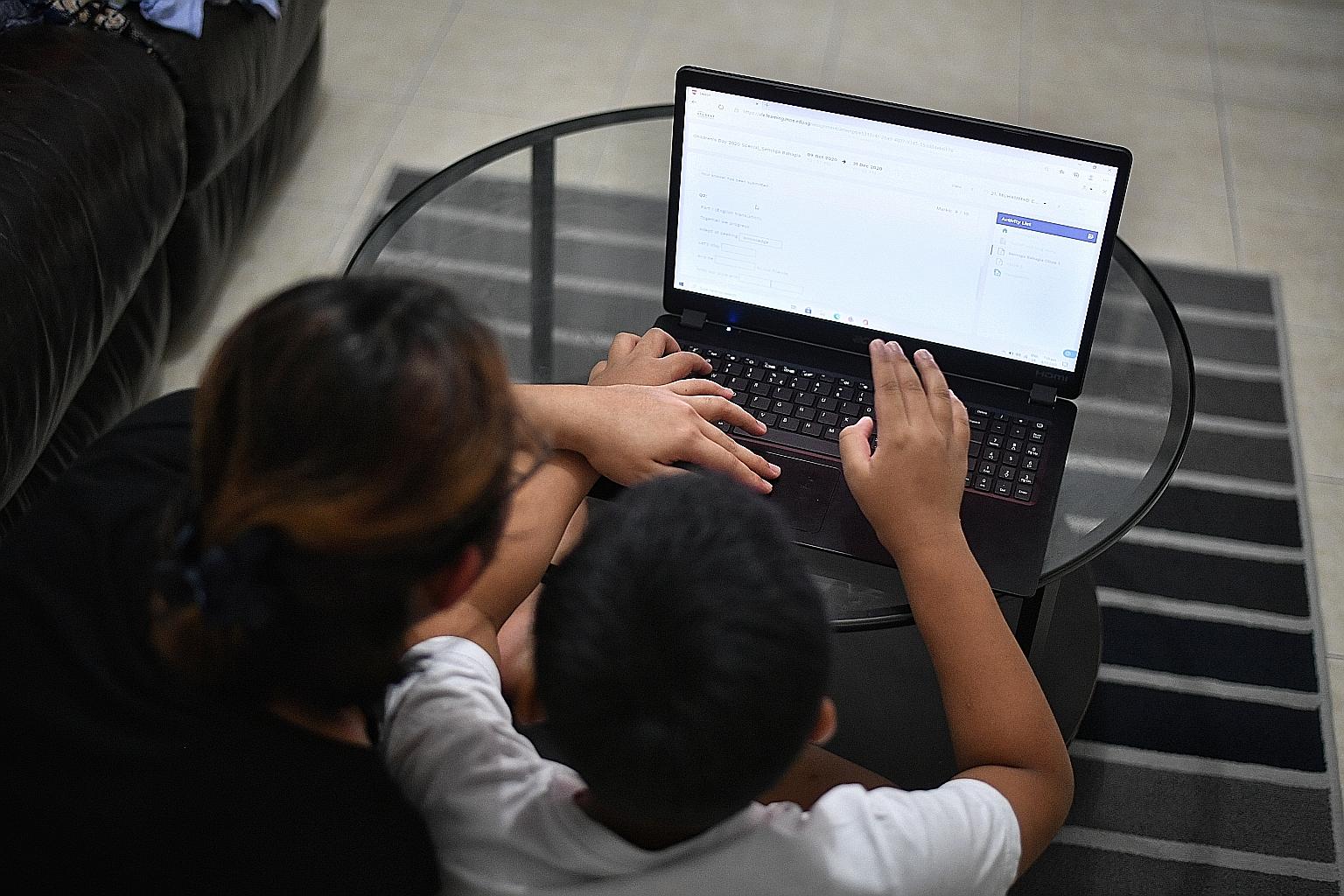 Ms Sarah, a single parent who declined to give her full name, helping her 10-year-old son with his home-based learning on Wednesday. She received a laptop under the NEU-PC Plus scheme after a referral by non-profit group AMP Singapore.