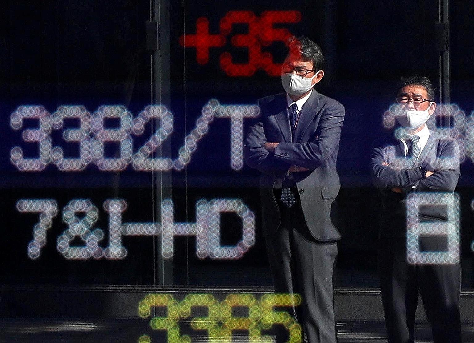 People outside a brokerage in Tokyo yesterday. Japan's Nikkei 225 ended up nearly 0.3 per cent. The positive tone in Asian equities came after Pfizer said its Covid-19 vaccine was over 90 per cent effective in preventing infection, marking the first 