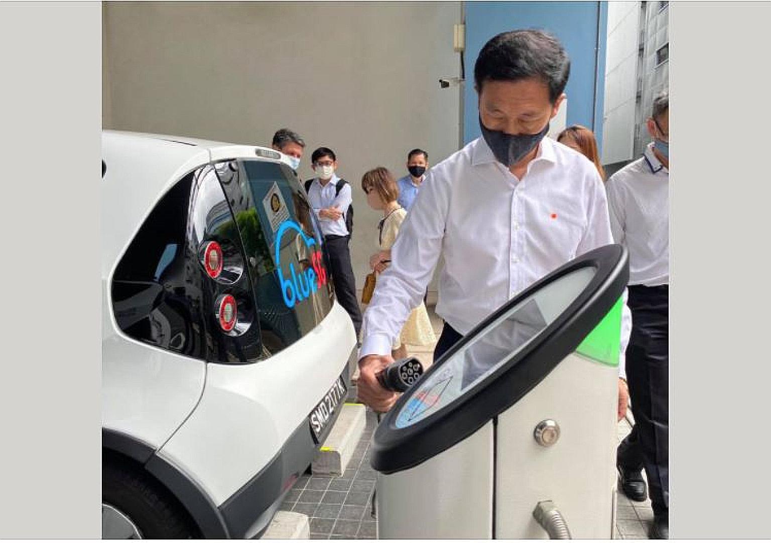 Transport Minister Ong Ye Kung beside a BlueSG electric vehicle (EV). He said the authorities are reviewing the plan to increase the number of EV-charging points to see if commercial parties could be roped in.