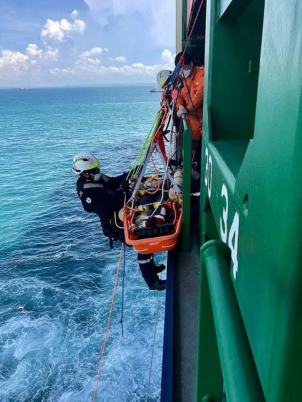 A Singapore Civil Defence Force marine specialist lowering the casualty on a stretcher to a heavy rescue vessel. The worker had injured his leg after falling down a hatch and was unable to move. PHOTO: SCDF/FACEBOOK