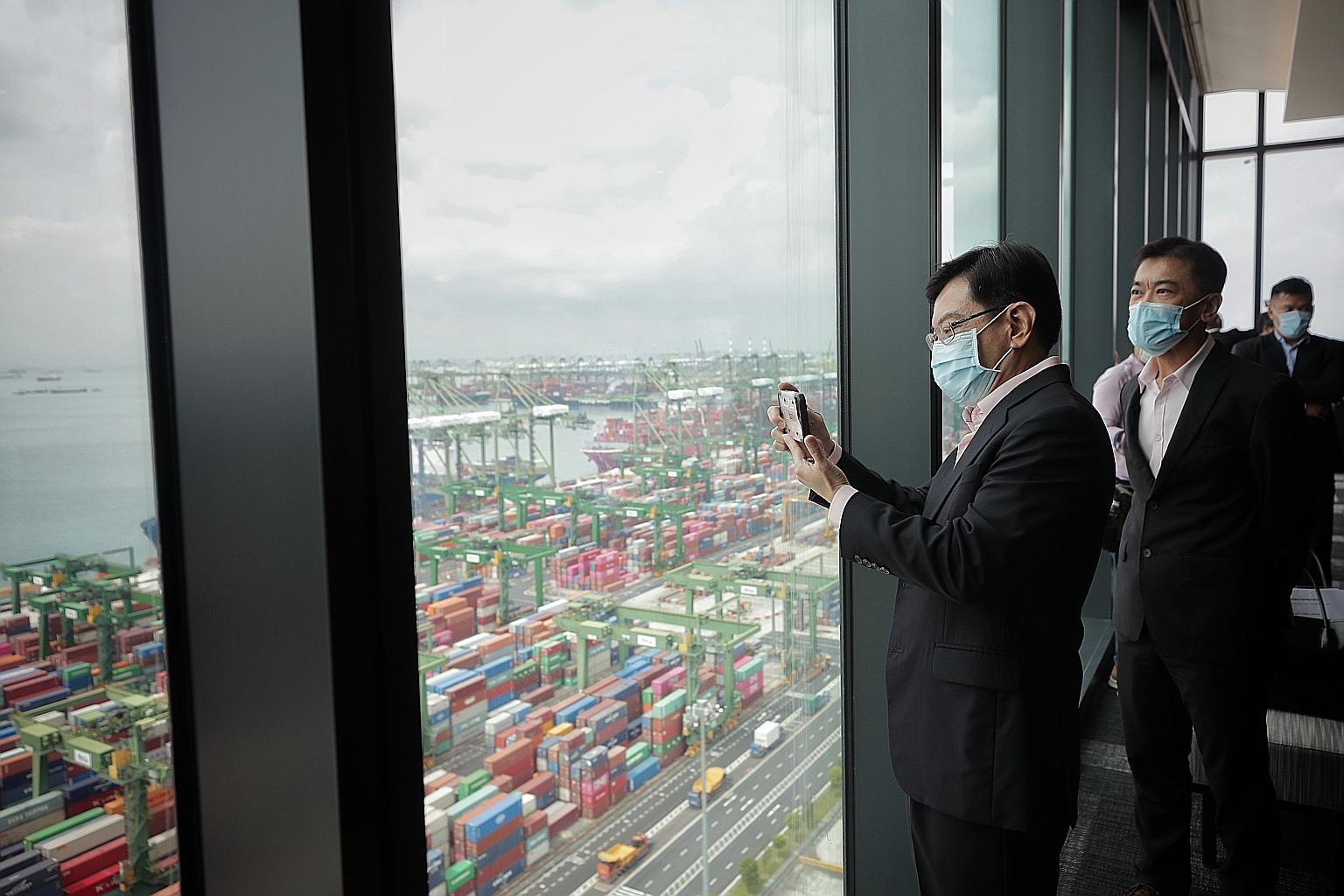 Deputy Prime Minister Heng Swee Keat taking a photo of Pasir Panjang Terminal and the Port of Singapore from the new PSA Horizons building yesterday, as Mr Ong Kim Pong, PSA's regional CEO for South-east Asia, looked on. Mr Heng and members of the Em