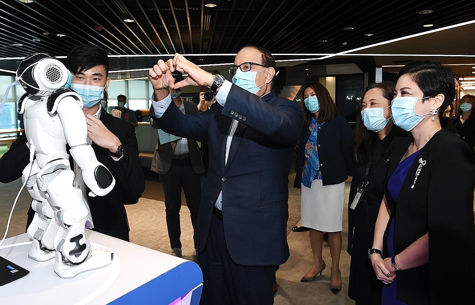 Communications and Information Minister S Iswaran making a gesture to Nao, a humanoid robot which can recognise hand gestures, during his visit to IBM yesterday. He was at the tech firm to witness the signing of the memorandum of intent between IBM a