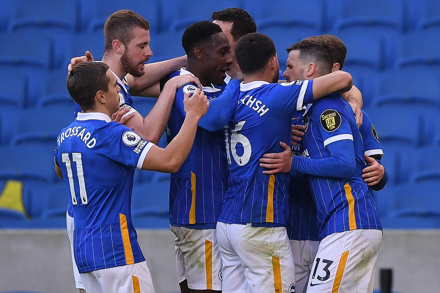 Brighton's Pascal Gross is mobbed by teammates after scoring his team's stoppage-time equaliser from the penalty spot yesterday. The VAR review punished EPL champions Liverpool's Andy Robertson for kicking Danny Welbeck's foot.