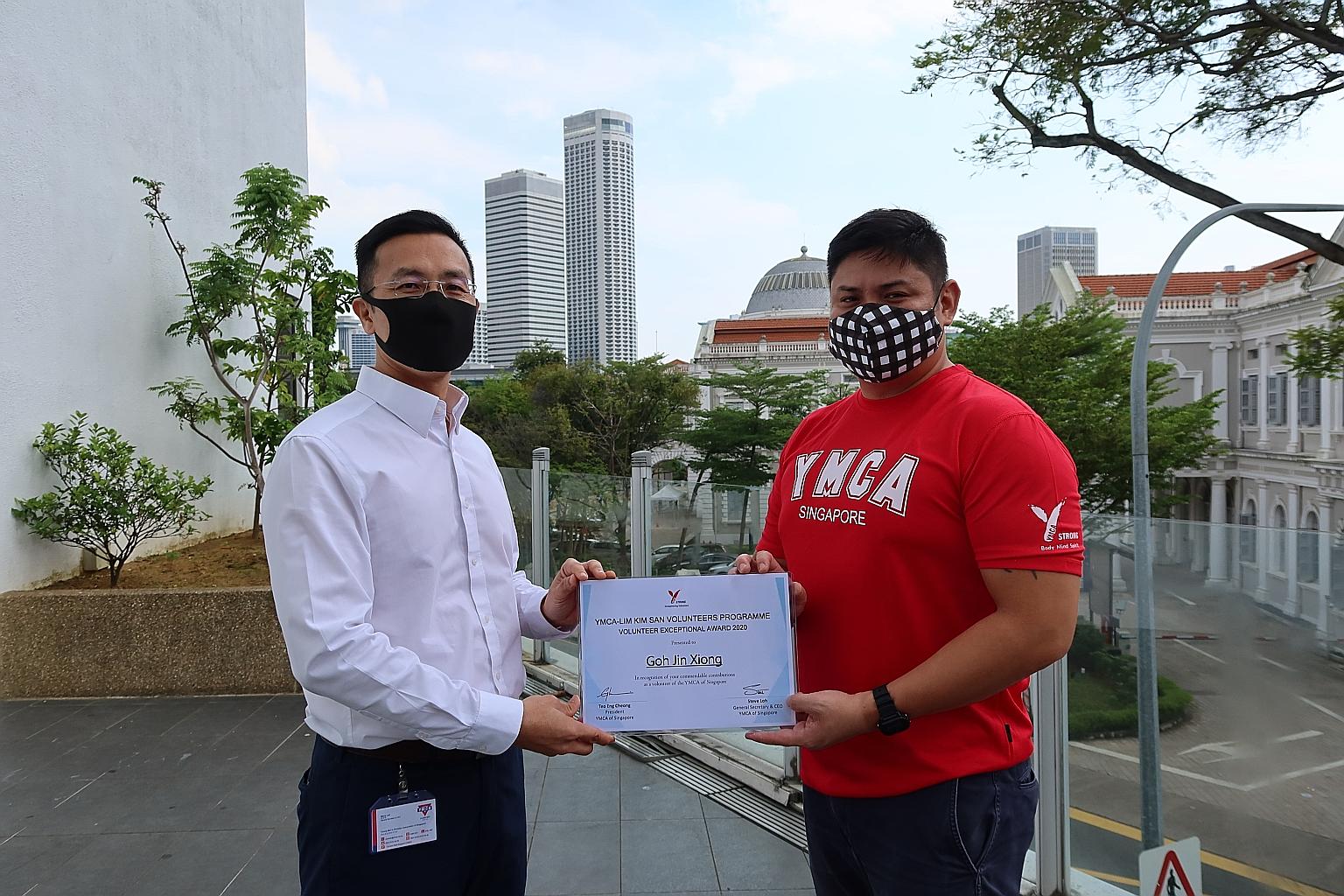 Sea Wheel travel agency transport manager Goh Jin Xiong (right) receiving the YMCA-Lim Kim San Volunteer Exceptional Award from YMCA chief executive and general secretary Steve Loh on Thursday.