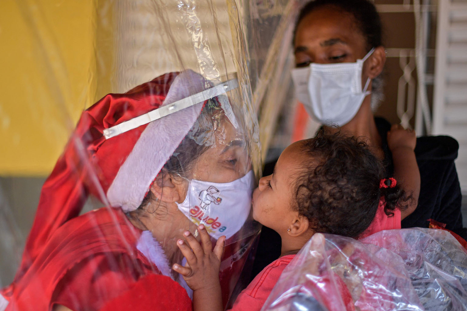 Ms Fatima Sanson, dressed up as Mrs Claus, kissing a child through a plastic "hug curtain" at a charitable event on Monday in Belo Horizonte in south-eastern Brazil. PHOTO: AGENCE FRANCE-PRESSE