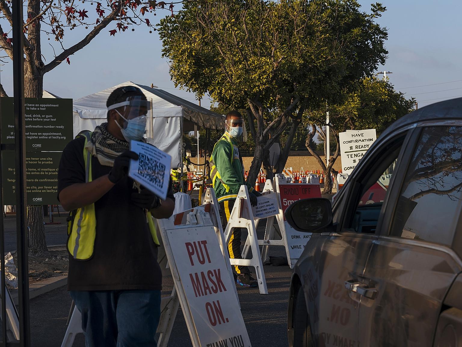 Workers guiding vehicles at the entrance of the Covid-19 drive-through testing site at the Crenshaw Christian Centre in Los Angeles on Friday. The US Food and Drug Administration on Friday authorised the vaccine for emergency use, after Britain becam