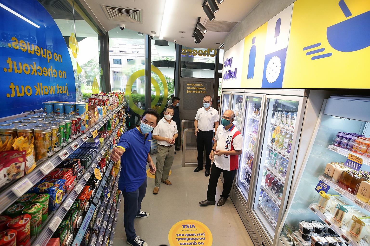Minister for Social and Family Development Masagos Zulkifli (right) being briefed by Cheers general manager Chua Boon Keat (in blue) at the new Cheers store in Our Tampines Hub yesterday, along with FairPrice's group CEO Seah Kian Peng (second from l