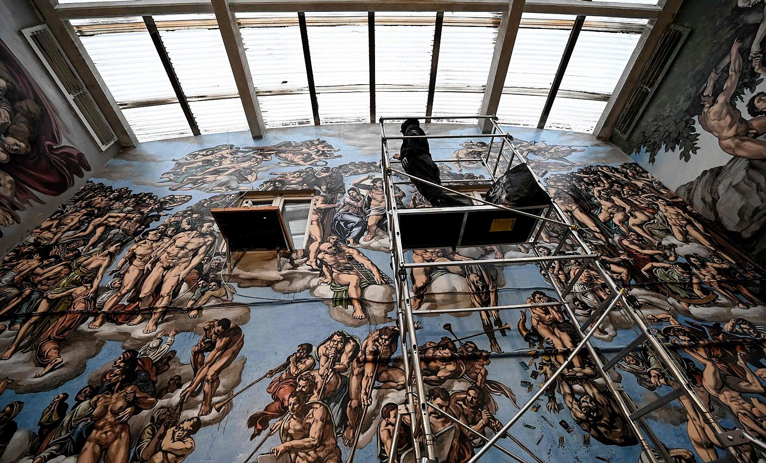 French artist Pascal Boyart aka PBoy painting his "Sistine Chapel Underground" fresco, in an abandoned warehouse in Ivry-sur-Seine, on the outskirts of Paris. His vision features Adam and Eve in their underwear, credit cards falling out of a horn of 