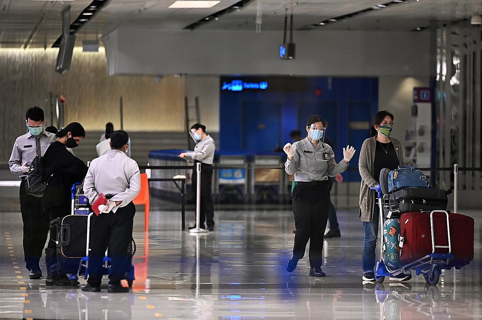 Security personnel with passengers arriving at Changi Airport Terminal 1 last week. Among yesterday's 24 new imported coronavirus cases were 13 Singaporeans or permanent residents who came back from Austria, India, Indonesia, Myanmar and the United K