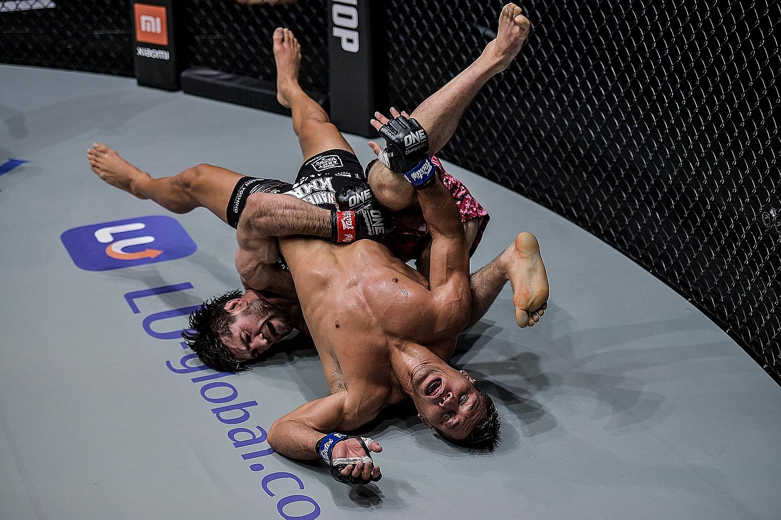 Russia's Marat Gafurov taking American fighter Lowen Tynanes down to the mat en route to a split-decision victory in their mixed martial arts lightweight bout at One Championship's Collision Course event at the Singapore Indoor Stadium last night. In