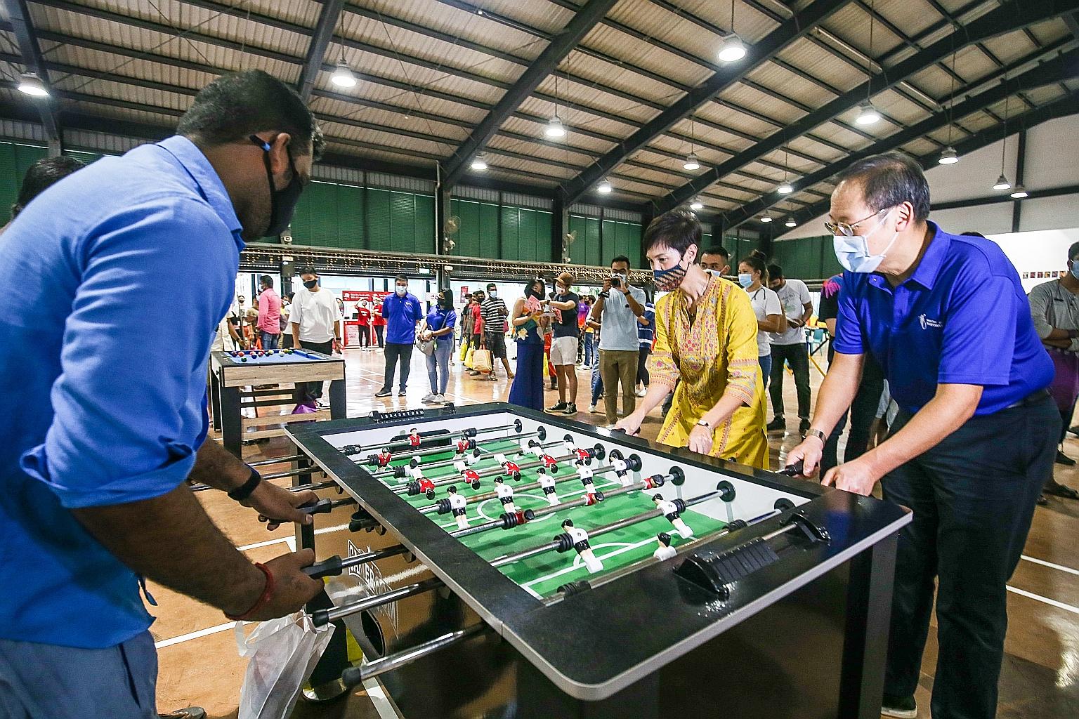 Manpower Minister Josephine Teo and Second Minister for Manpower Tan See Leng playing table football with a migrant worker at Terusan Recreation Centre in Jurong yesterday.