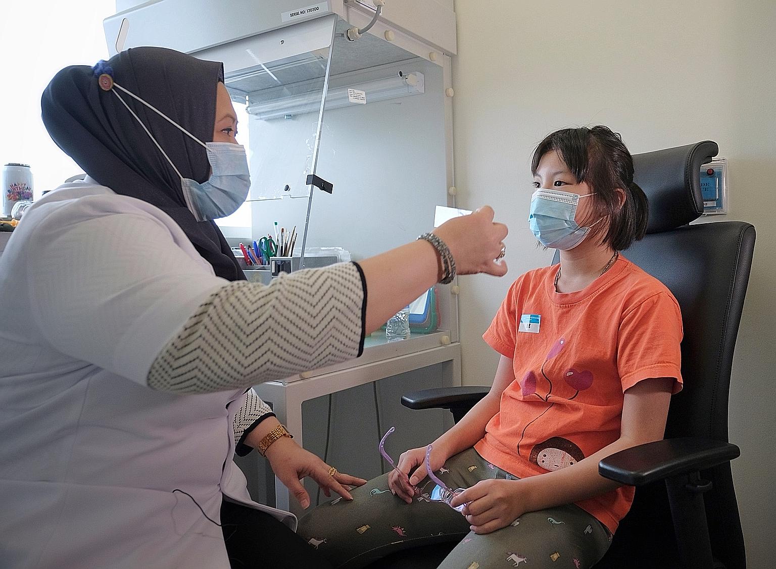 National University Hospital ocularist Suriya Abu Waled checking Claire Lim's eye prosthesis at her clinic in the NUH Medical Centre last Friday. Claire, 10, was born with one eye abnormally small and dysfunctional.