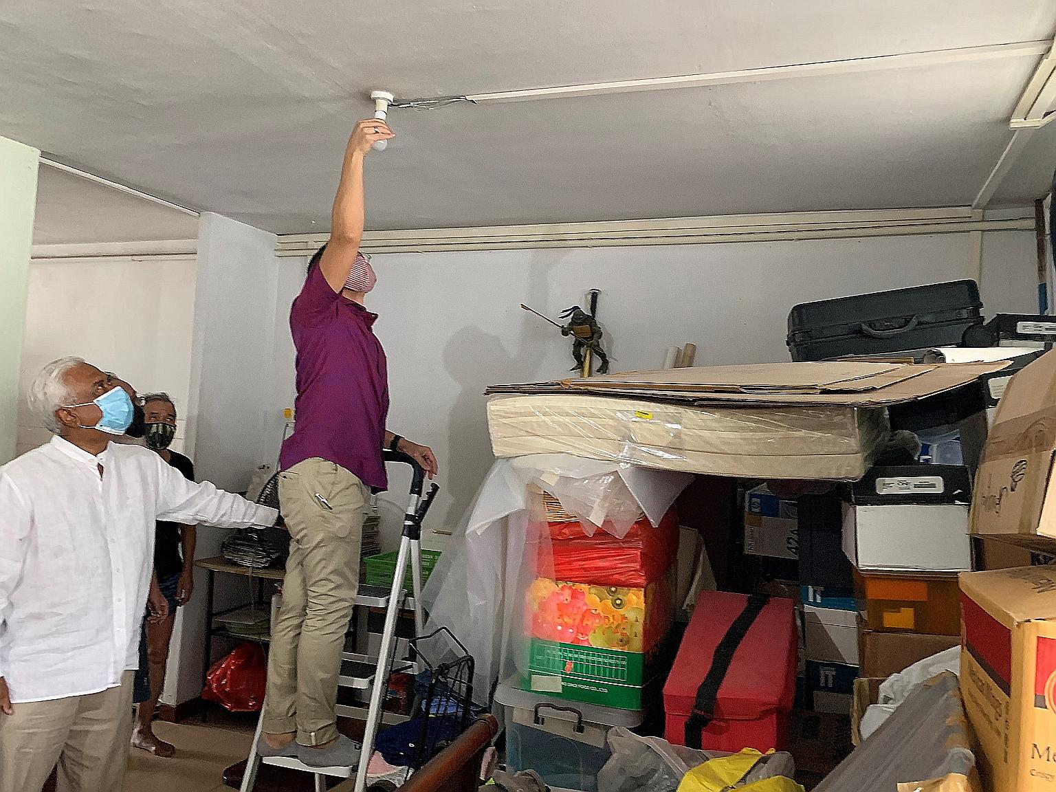 Minister in the Prime Minister's Office Maliki Osman changing a light bulb in a beneficiary's home yesterday. The distribution of energy-saving light bulbs is aimed at helping households cut costs.