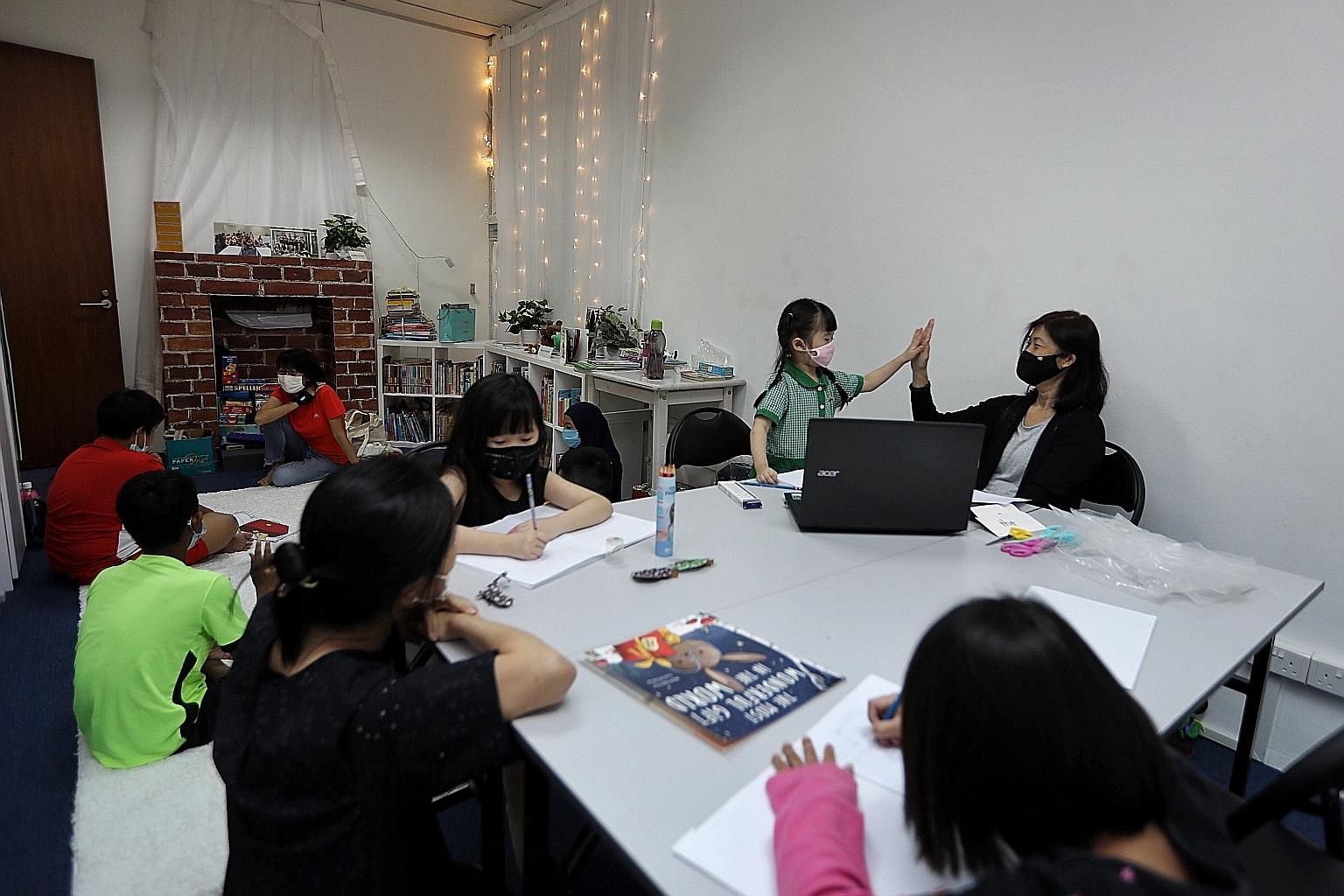 Mrs Synnetta Ho, a 58-year-old volunteer with KidzCare, giving Tan Wey Xyen a high five after the six-year-old successfully pronounced a word last Thursday in one of the rooms sponsored by ESR-Reit in Viva Business Park in Chai Chee. The volunteer gr