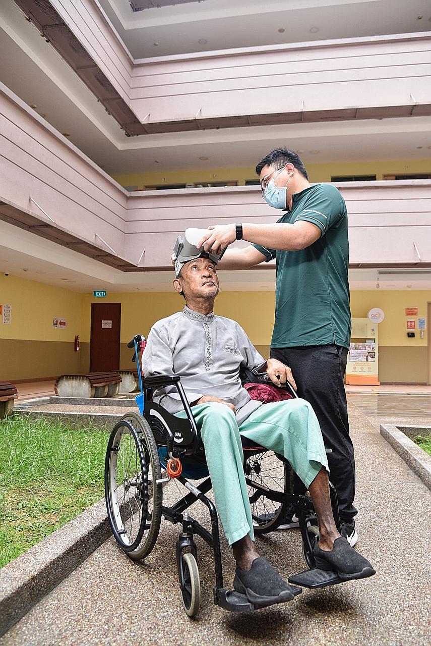 Jamiyah Nursing Home therapy assistant Mark Bartolome adjusting a virtual reality headset for Mr Abdul Rahim Abdullah, 64, a resident at the home whose mobility was affected by a stroke. Through the headset, Mr Rahim is able to go on a virtual trisha