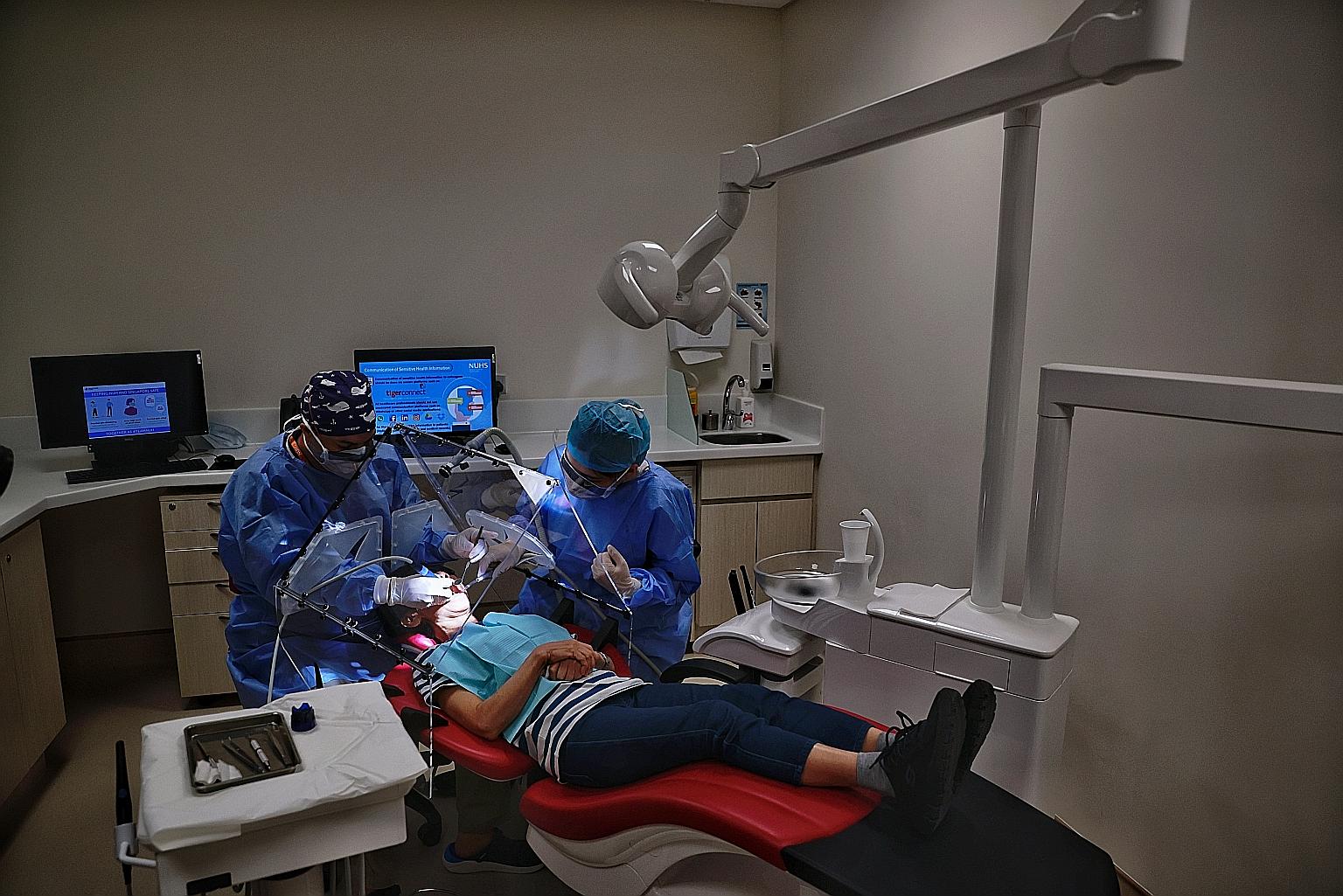 NUS Faculty of Dentistry's Dr Intekhab Islam (at left) and a dental assistant demonstrating the use of the Dental Dart for treatment with a mock patient at the National University Centre for Oral Health on Monday. ST PHOTO: KEVIN LIM