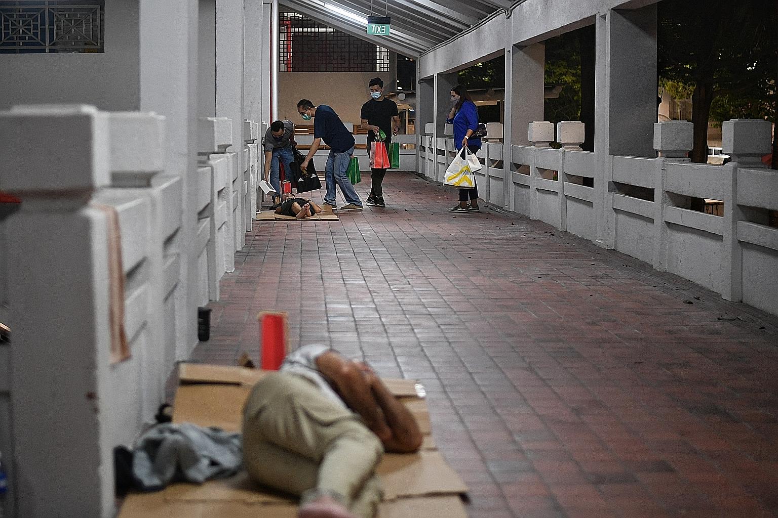 Parliamentary Secretary Eric Chua (left) joining Catholic Welfare Services social workers in distributing bags packed with toiletries, food and drinks to those sleeping in the streets in Bras Basah area on Christmas Day. ST PHOTO: ARIFFIN JAMAR