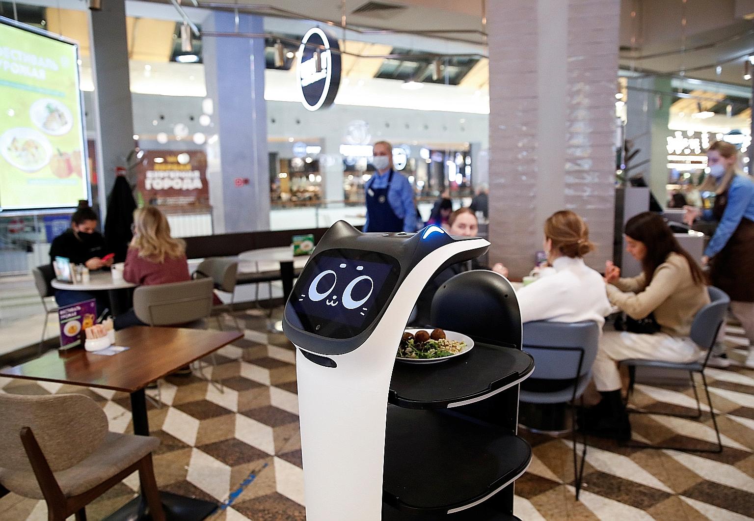 Customers at a cafe in Moscow which is using a robotic waiter to provide contactless service amid the Covid-19 outbreak. But complex and emotionally difficult tasks are still best handled by front-line staff. PHOTO: REUTERS