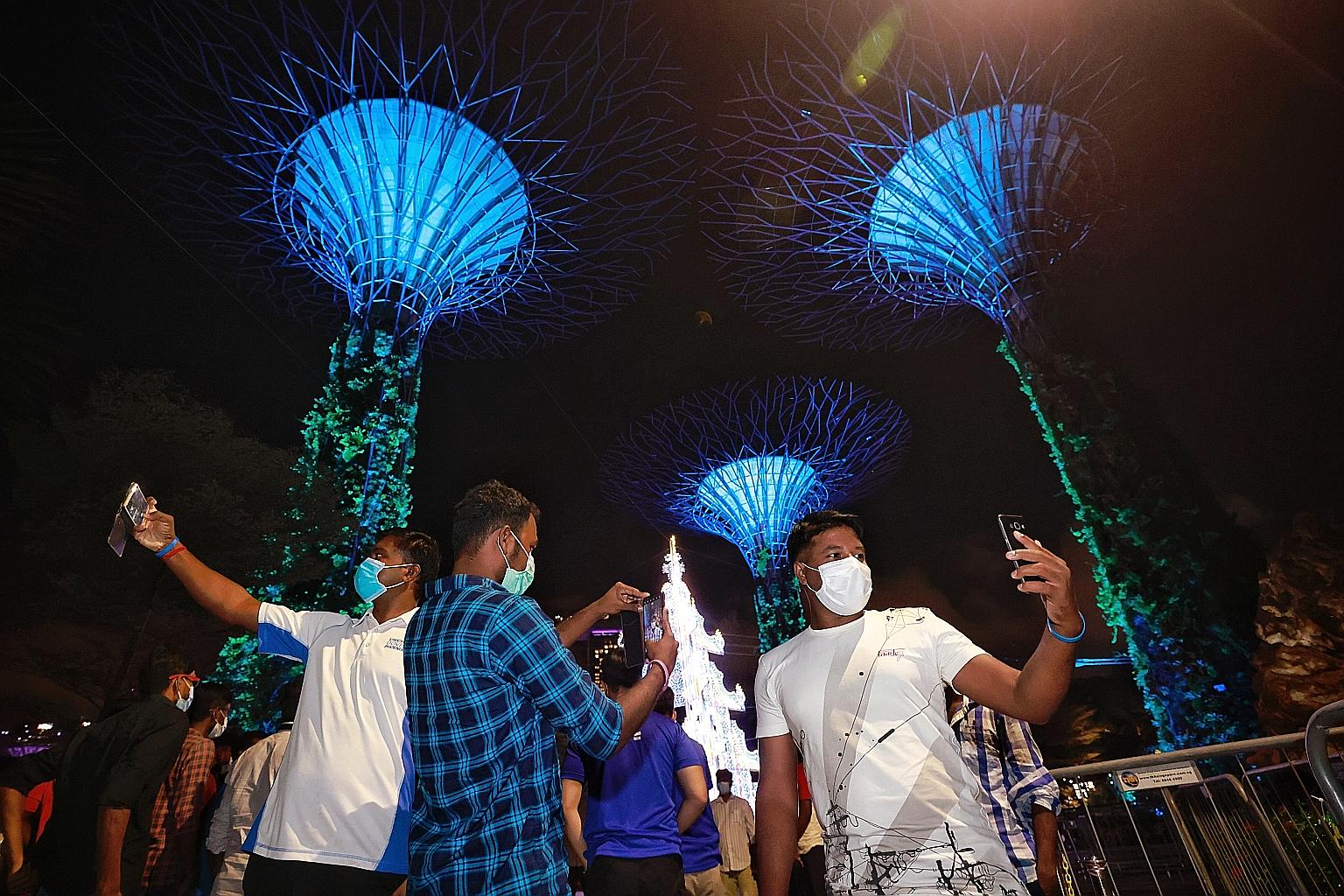 Migrant workers taking selfies yesterday at a Gardens by the Bay stopover during a bus tour organised by social enterprise ItsRaining Raincoats.