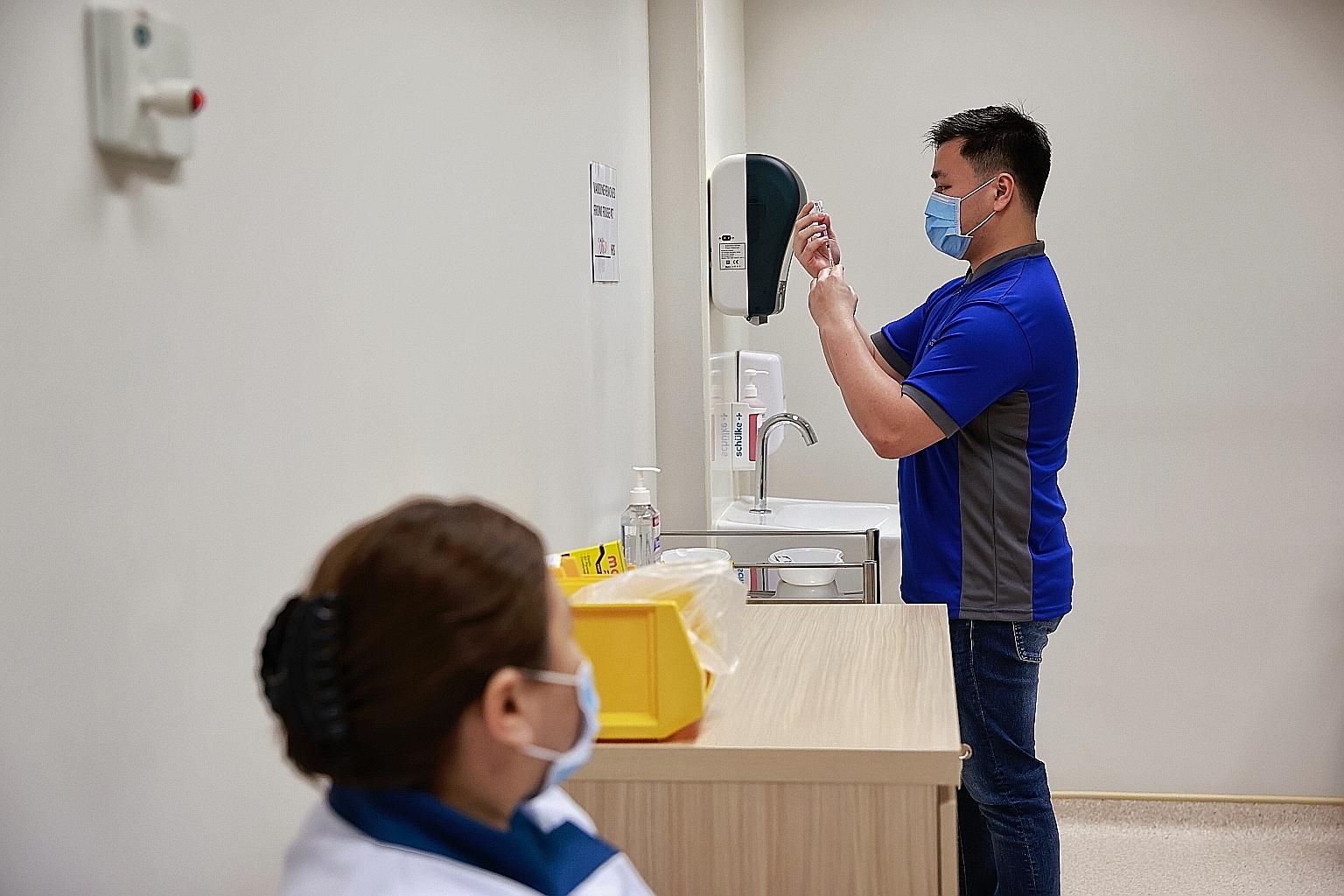 Senior staff nurse Kho Wei Lian, 26, preparing a Covid-19 vaccination jab yesterday at the National Centre for Infectious Diseases, where healthcare staff were among the first Singaporeans to receive the Covid-19 vaccine developed by Pfizer and BioNT