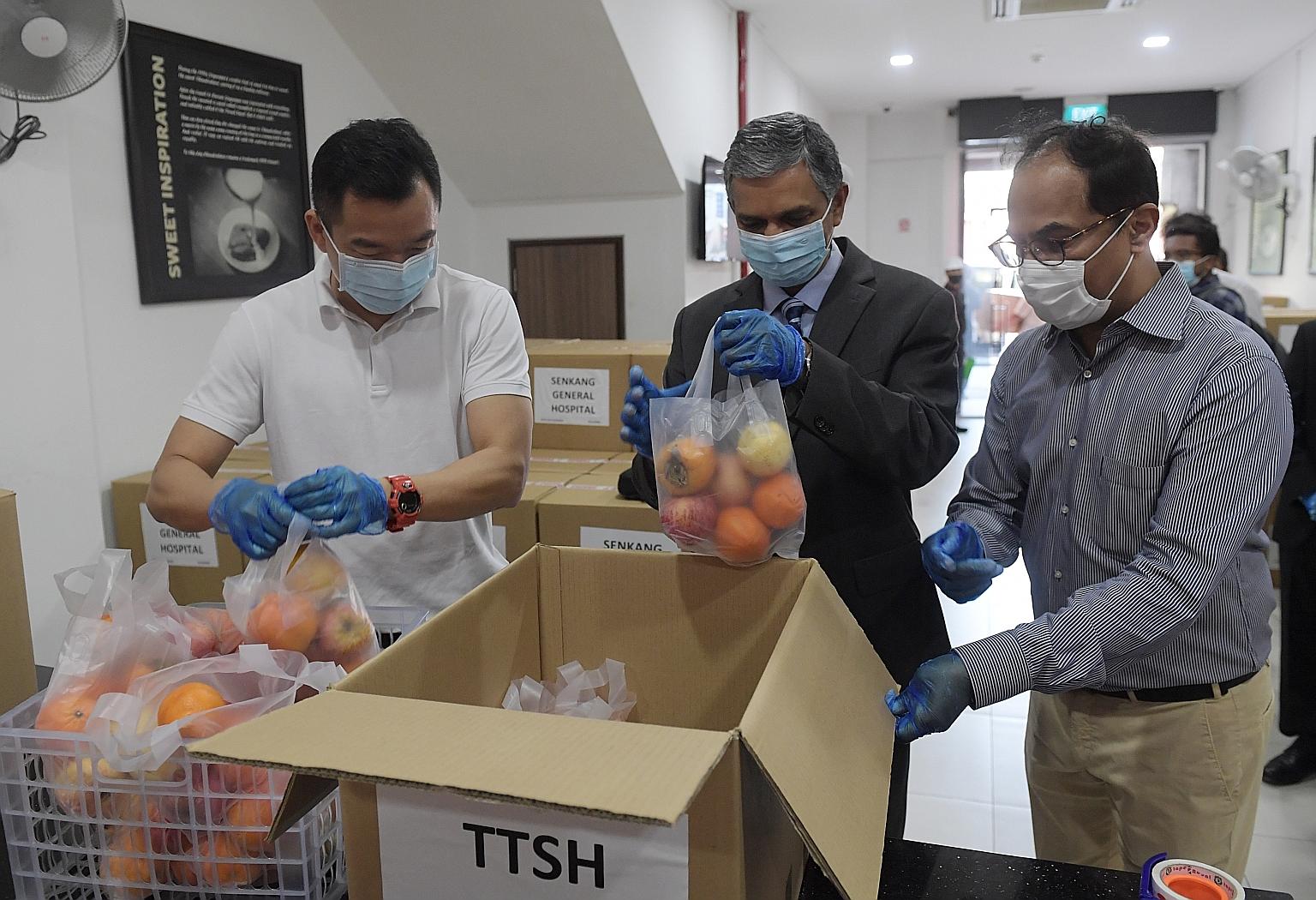 From far left: Parliamentary Secretary for Culture, Community and Youth Eric Chua, India's High Commissioner to Singapore Periasamy Kumaran, and Mavalli Tiffin Rooms operations director Raghavendra Shastry preparing the fruit boxes.