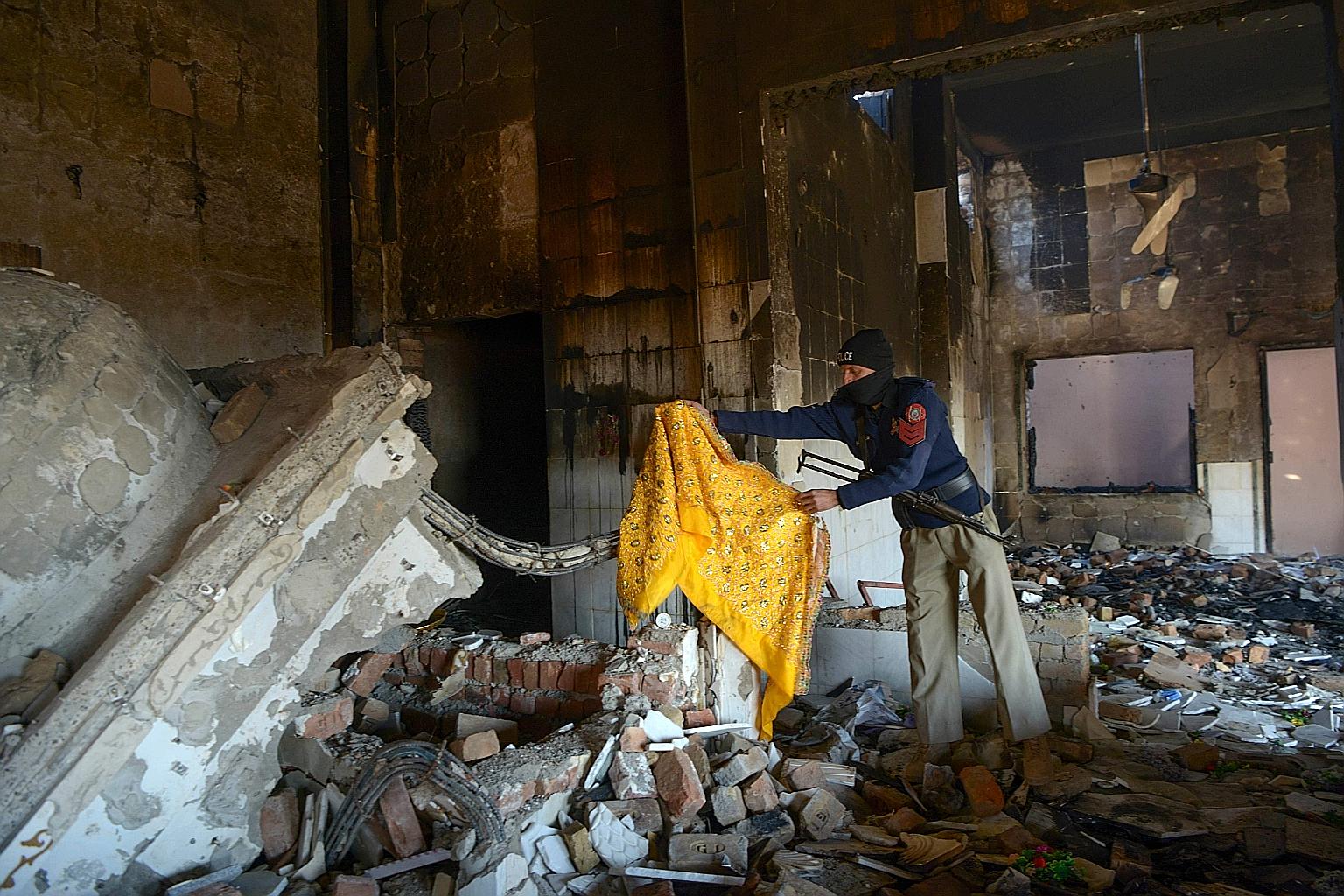 A policeman inspecting a damaged Hindu temple in a remote village in north-west Pakistan yesterday, after it was attacked and set ablaze on Wednesday. Video clips circulating on social media showed men breaking apart the temple walls using sledgehamm