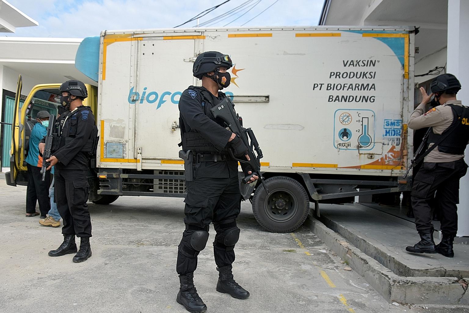 Armed police officers standing guard next to a truck containing Sinovac's Covid-19 vaccine during its distribution in Pekanbaru, Riau province, yesterday. President Joko Widodo and his Cabinet will kick off the nationwide vaccination programme by get