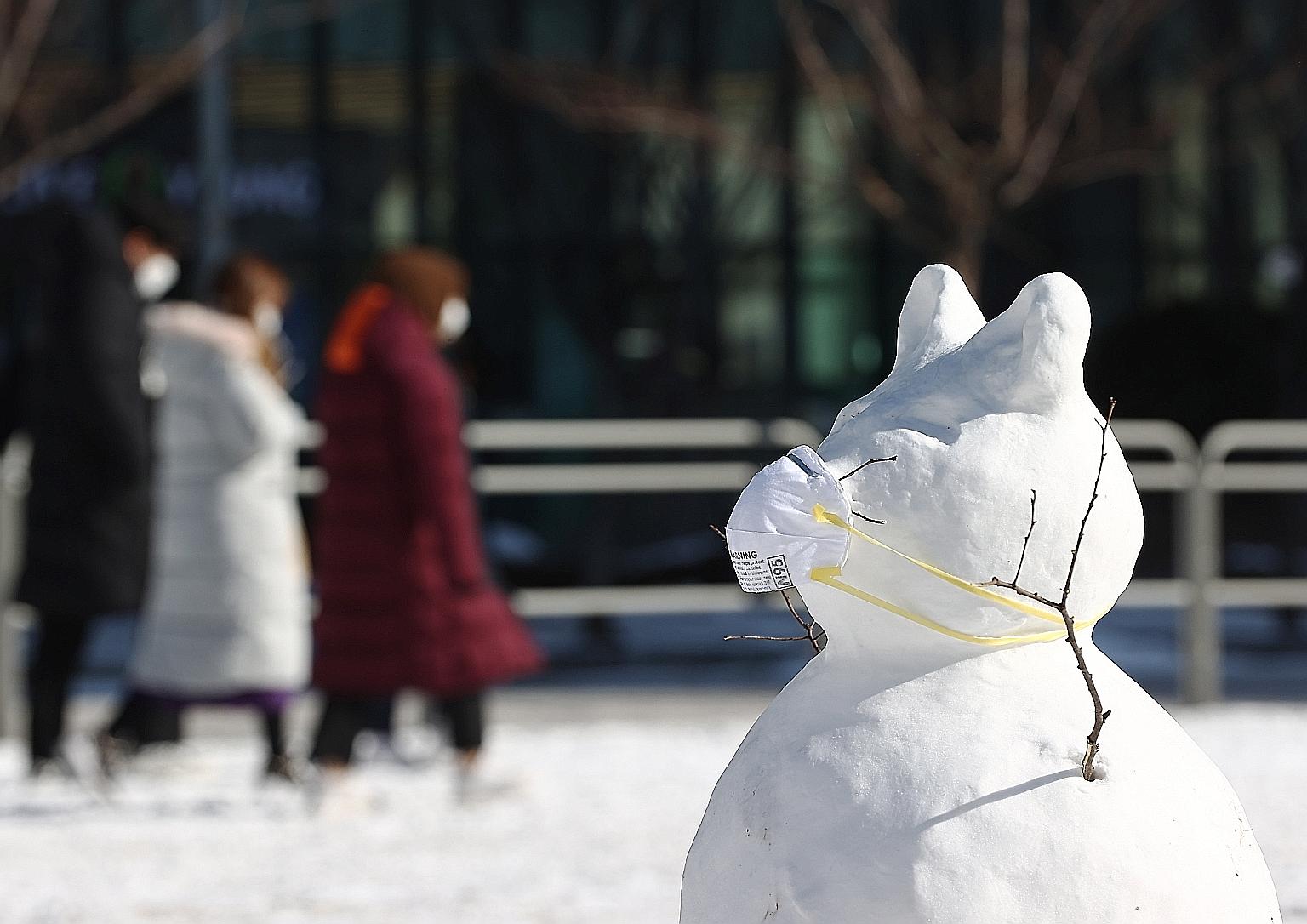 A masked snowman standing in front of an outdoor Covid-19 testing station in Seoul yesterday, as heavy snowfall hit South Korea. Some experts attributed the cold weather to a lower carbon footprint last year, with factories shutting down during the c