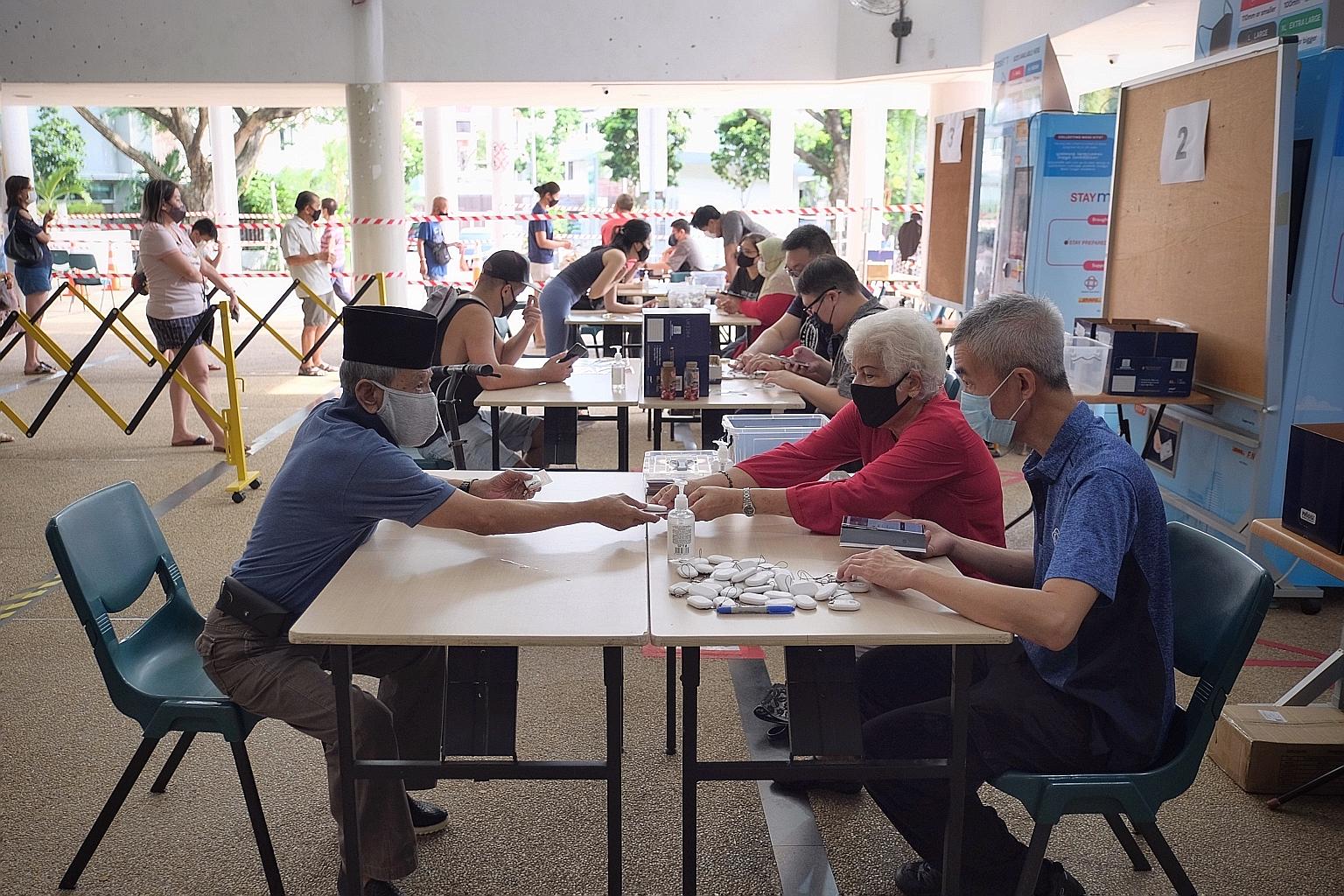 Residents collecting their TraceTogether tokens at a community centre last month. Some observers feel that limiting the use of the data would help balance the need to fight Covid-19 with the need to fight serious crime. ST PHOTO: GAVIN FOO