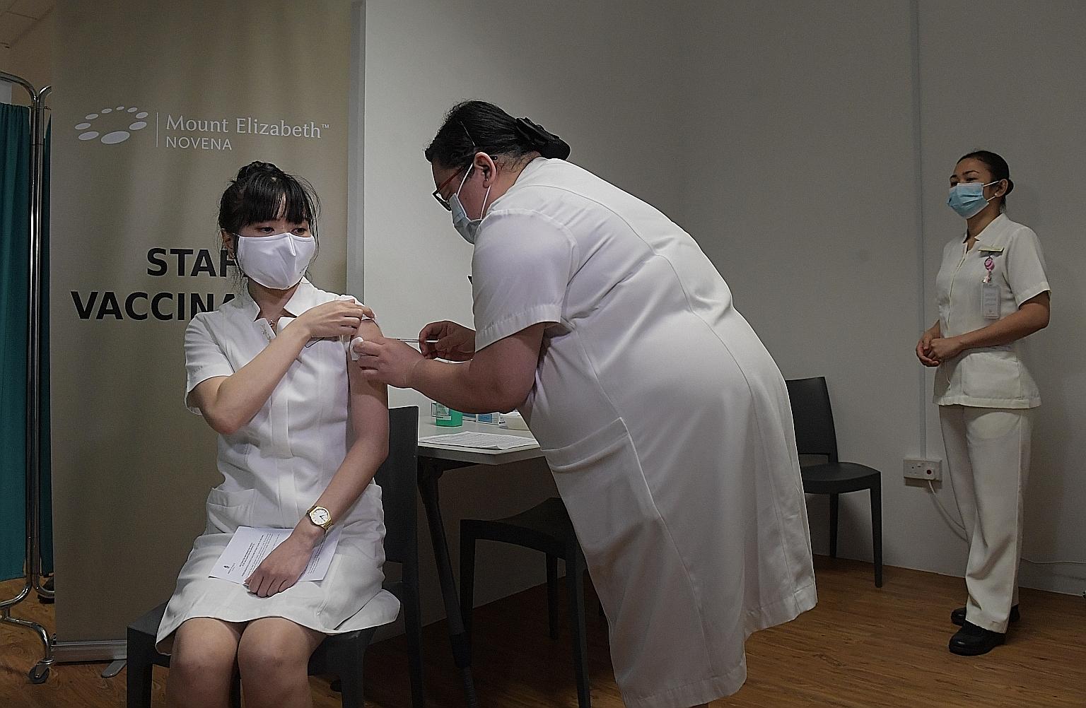 Ms Wan Yuting, a senior staff nurse at Mount Elizabeth Novena Hospital, receiving the Pfizer-BioNTech vaccine yesterday. Among those inoculated were Parkway Pantai's senior executives and some of the group's infectious disease physicians, who said th
